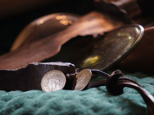 Nahaufnahmen zweier alter Münzen und weiteren verschwommenen Gegenständen im Hintergrund